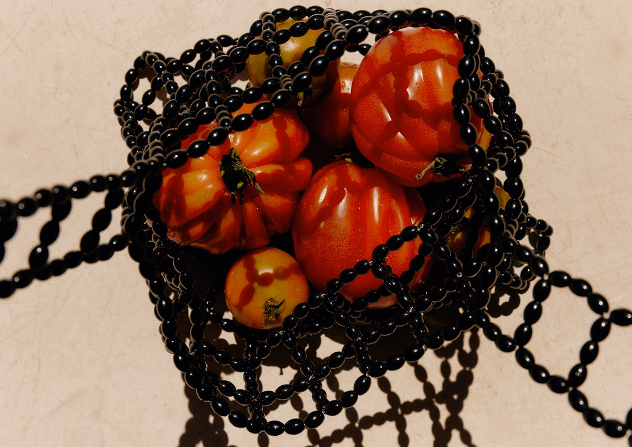 Tomatoes held in a black beaded bag
